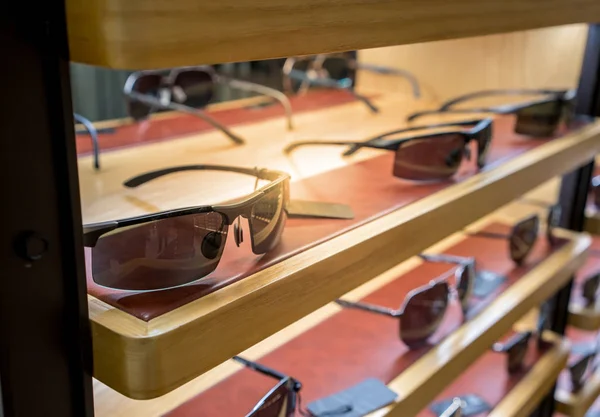 Různé sluneční brýle v obchodě zobrazovat police. — Stock fotografie