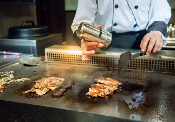 Mão de Chef adicionando sal no bife na panela quente na frente de c — Fotografia de Stock