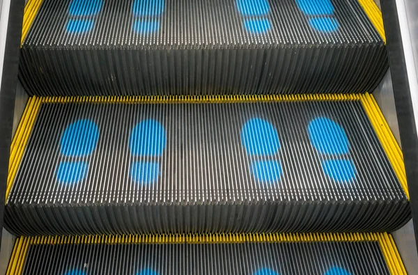 Escalera escaleras mecánicas en el centro comercial subiendo con footpri azul —  Fotos de Stock