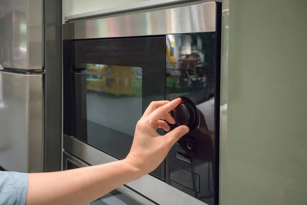 Manos de mujer ajustando el botón de temporización en el microondas — Foto de Stock