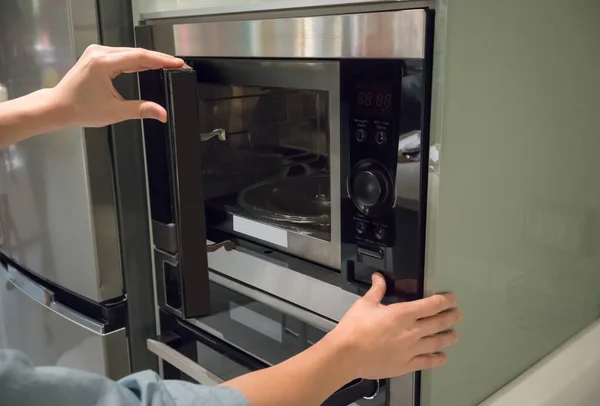 Manos de mujer pulsando el botón para abrir la puerta del microondas — Foto de Stock