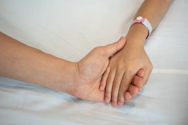 El padre sostiene la mano de un niño enfermo en un hospital . — Foto de Stock