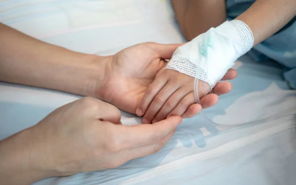 Manos de la madre sosteniendo su mano del bebé paciente con intraveno salino — Foto de Stock