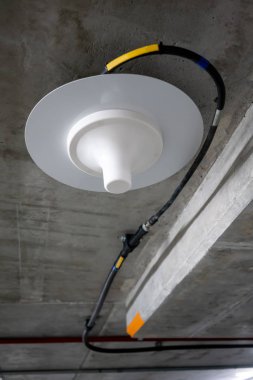 Neon lig altında beton tavan boyunca çalışan elektrik telleri