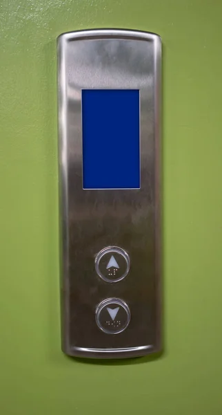 Silver elevator buttons panel with digital screen against green