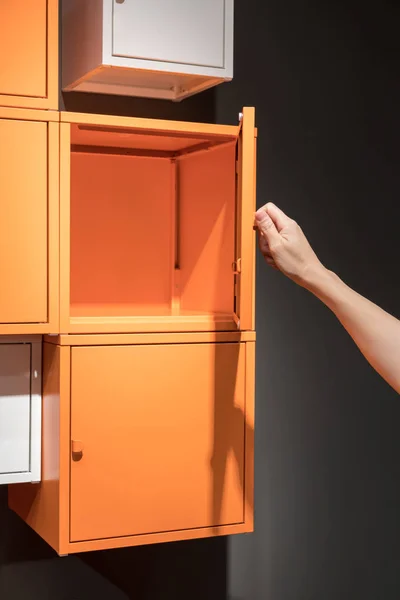 Hand öffnet die orangefarbenen Metallschränke, die an der schwarzen Wand hängen — Stockfoto