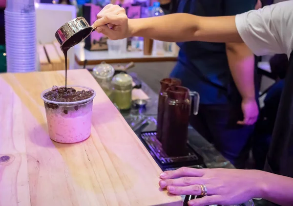 Woman hand holding silver cup adding chocolate syrup on top of p — Stock Photo, Image