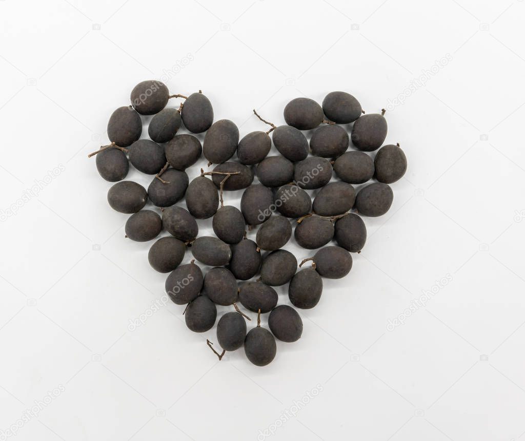 Heart shape of dried Black Dialium with shell isolated on white background. Traditional tropical fruit. Velvet tamarind.
