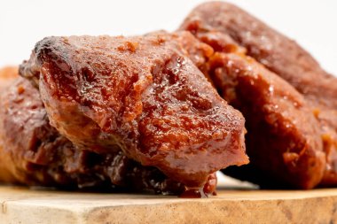 Beyaz arka planda izole edilmiş ahşap kesme tahtasında Çin usulü kızarmış barbekü kırmızısı domuz eti yakın.