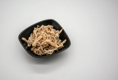 Beyaz arka planda izole edilmiş siyah kasede kurutulmuş papaya dilimleri. Tayland usulü tatlı ve tuzlu meyve atıştırmalıkları..