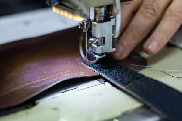 Man sewing a leather for making a shoe. Shoemaker working in the shoe workshop. shoe sewing machine in focus.