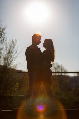 Batan güneşin arka planda sarılma kadın ve erkek. Siluet.