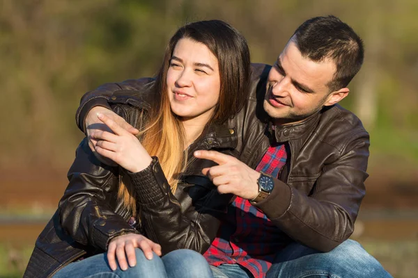 Liebespaar sitzt auf der Eisenbahn. Beide zeigen mit dem Finger. — Stockfoto