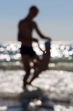 Bulanık baba ve oğul kumsalda oynarken.