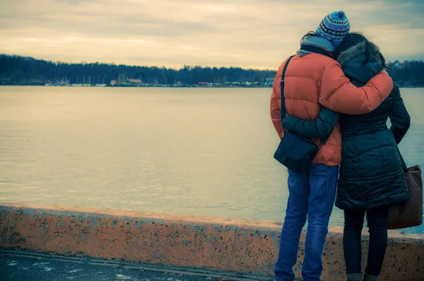 Άνδρας και γυναίκα στέκεται αγκάλιασε και αναζητούν στη θάλασσα. — Φωτογραφία Αρχείου
