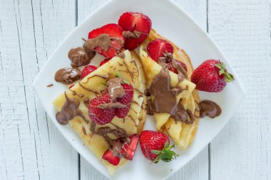 Krep çilek ile çikolata ile drizzled. Beyaz ahşap zemin üzerinde. Üstten Görünüm.