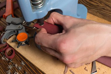 Ana basın ile cilt üzerinde çalışıyor. Araçları ve aksesuarları ile dağınık kahverengi ahşap masa.