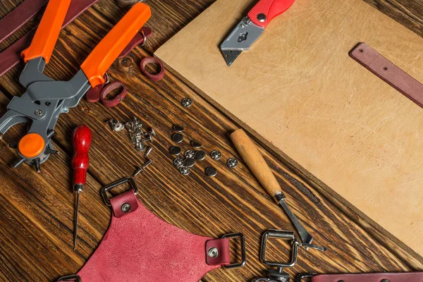 갈색 나무 테이블에 흩어져 도구와 작업 가죽을 위한 액세서리. — 스톡 사진