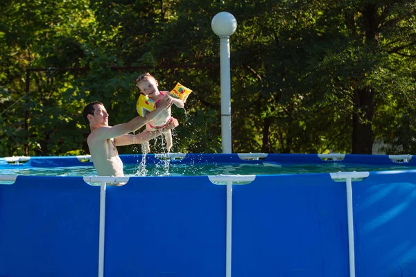 Glückliche Familie spielt im Schwimmbad. Sommerferienkonzept. — Stockfoto