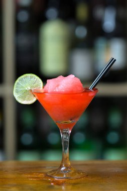 Kırmızı kokteyl bar counter ahşap ayakta kireç ile süslenmiş buz ile. Arka plan rafa şişe ile.