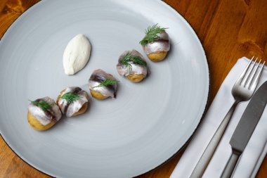 Beyaz plaka üzerinde genç patates ile ringa balığı. Ahşap arka plan. Yatay olarak çerçeveli atış.