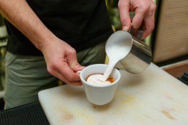 Profesyonel barista kahve yapmak için süt dökme.