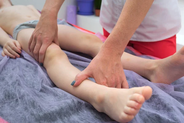 Massaggio ai piedi. Massaggiatrice fisioterapista che fa un massaggio alle gambe a un ragazzo in clinica . — Foto Stock