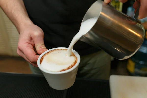 Profesjonalnych barista wlewając mleko do kawy. Płytkiej głębi ostrości. — Zdjęcie stockowe