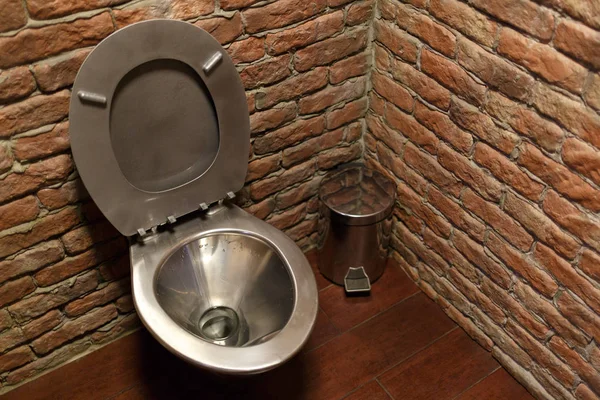 Stainless steel toilet bowl on brick wall background. — Stock Photo, Image