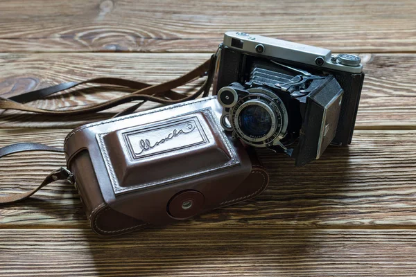 Chisinau, Republic of Moldova - March 14, 2018: The old Soviet medium format rangefinder camera Moskwa-5 and leather case. Wooden background. — Stock Photo, Image