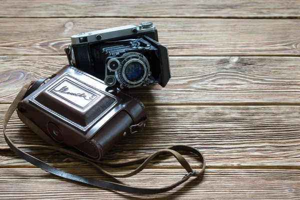 Chisinau, Republic of Moldova - March 14, 2018: The old Soviet medium format rangefinder camera Moskwa-5 and leather case. Wooden background. — Stock Photo, Image