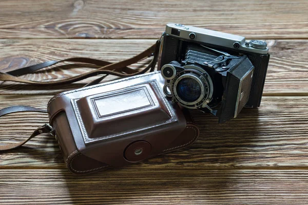 The old medium format rangefinder camera and leather case. Wooden background. — Stock Photo, Image