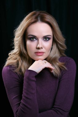 Siyah arka plan üzerine hafif kıvırcık saçlı güzel model portresi. Yardım için çenesinin dinlenmiş. Dikey olarak çerçeveli atış.