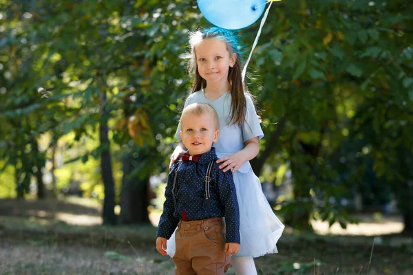 Familjeliv. Broder och syster i parken. Ballonger över deras huvuden. — Stockfoto