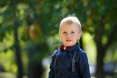 Doğanın arka planında küçük şirin bir çocuğun portresi. Parkta yürü. Aile hayatı.