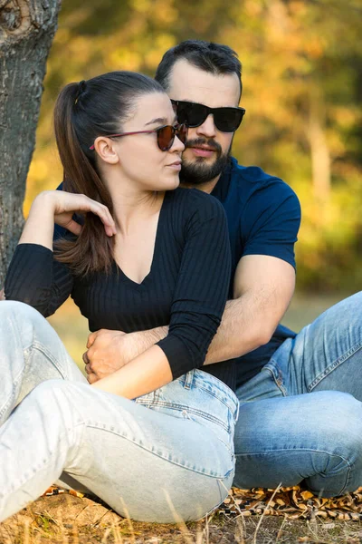 Portrait d'un homme et d'une femme en lunettes de soleil dans les bois. Jeune couple élégant sur fond de nature. Soirée d'automne chaude dans la forêt . — Photo