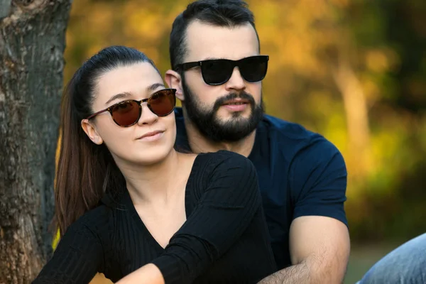 Porträt eines Mannes und einer Frau mit Sonnenbrille im Wald. junges stilvolles Paar vor dem Hintergrund der Natur. warmer Herbstabend im Wald. — Stockfoto