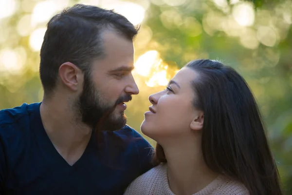 Portret młodej pięknej pary w parku. Patrzą na siebie. W tle liści drzew. — Zdjęcie stockowe