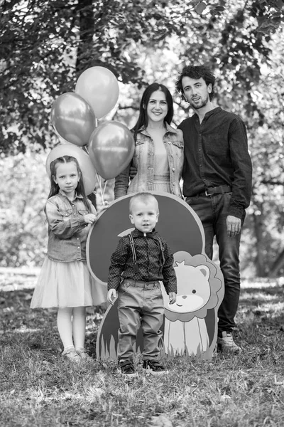 Familjeliv. Porträtt av föräldrar och deras barn i parken. Födelsedag för en tvåårig pojke. Dekor med nummer två med lejon och ballonger. — Stockfoto