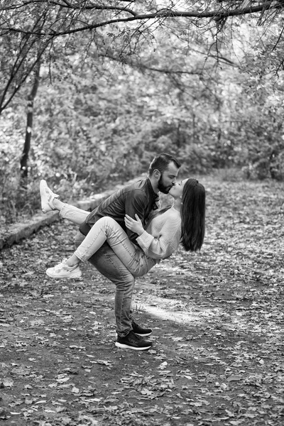 Junges schönes Paar im Park. Ein Mann hält eine Frau auf dem Arm. im Hintergrund Herbstwald. — Stockfoto