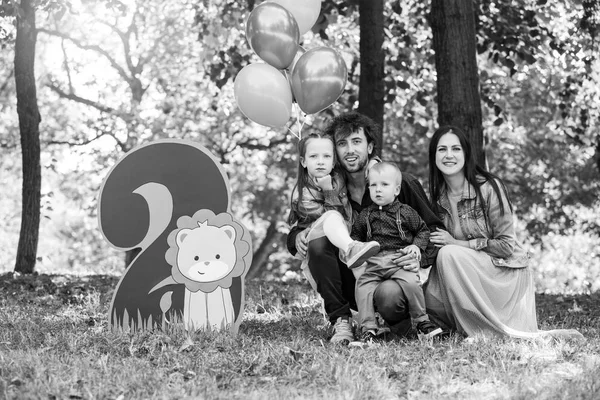 Сімейне життя. Портрет батьків та їхніх дітей у парку. День народження дворічного хлопчика. Декор з номером два з левами і повітряними кулями . — стокове фото