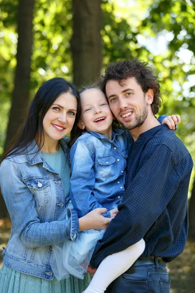 Family life. Portrait of parents and their daughter on the background of nature.