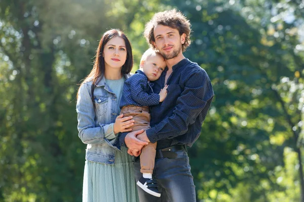 Family life. Portrait of parents and their son on the background of nature. Walk in park.