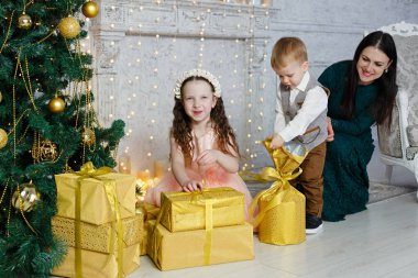 Çocuklar ve anneleri Noel hediyelerini açarlar. Evde yeni yıl odası var. Noel neşesi. Yaşam tarzı, aile ve tatil.