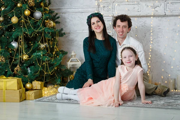 Noel ağacında genç ve mutlu bir aile. Ebeveynler ve kızları yeni yılı kutluyorlar. Evde yeni yıl odası var. Noel neşesi. Yaşam tarzı, aile ve tatil.
