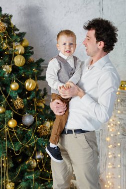 Oğlu ve babası Noel ağacında. Evde yeni yıl odası var. Noel neşesi. Yaşam tarzı, aile ve tatil.