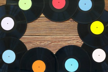 Ahşap masa arkaplanındaki Retro vinil plaklar. Çok renkli etiketler var. Üst Manzara. Kopyalama alanına yer.