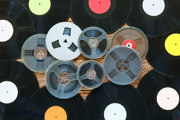 Old vintage bobbins, vinyl records on a wood table background. Multicolored labels. Top view.