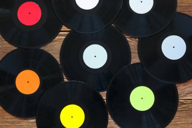 Ahşap masa arkaplanındaki Retro vinil plaklar. Çok renkli etiketler var. Üst görünüm.