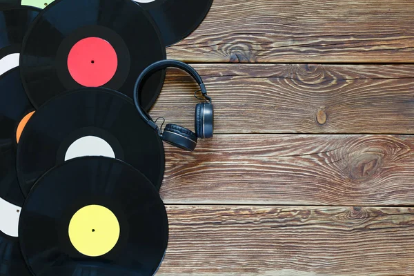 Retro-Schallplatten und Kopfhörer auf Holztischhintergrund. Bunte Etiketten. Ansicht von oben. Platz zum Kopieren von Raum. — Stockfoto